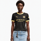 Manchester City 2026/27 away women's jersey — front on female model; AI-assisted background and framing edit